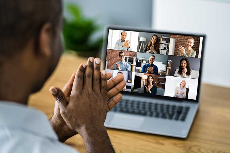 Remote worker looks at video call colleagues on laptop screen