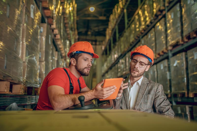 A manager and employee have a tough conversation in a manufacturing warehouse work setting